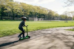 garçon conduisant une trottinette verte